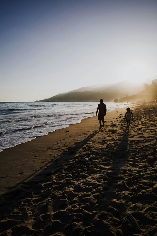Padre e hijo caminando en una playa del Pacífico